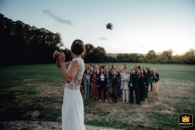 Op Domaine de Neuville, Yvelines, Frankrijk, gooit een mooie bruid haar boeket naar een groep opgewonden meisjes die reikhalzend wachten om te trouwen.